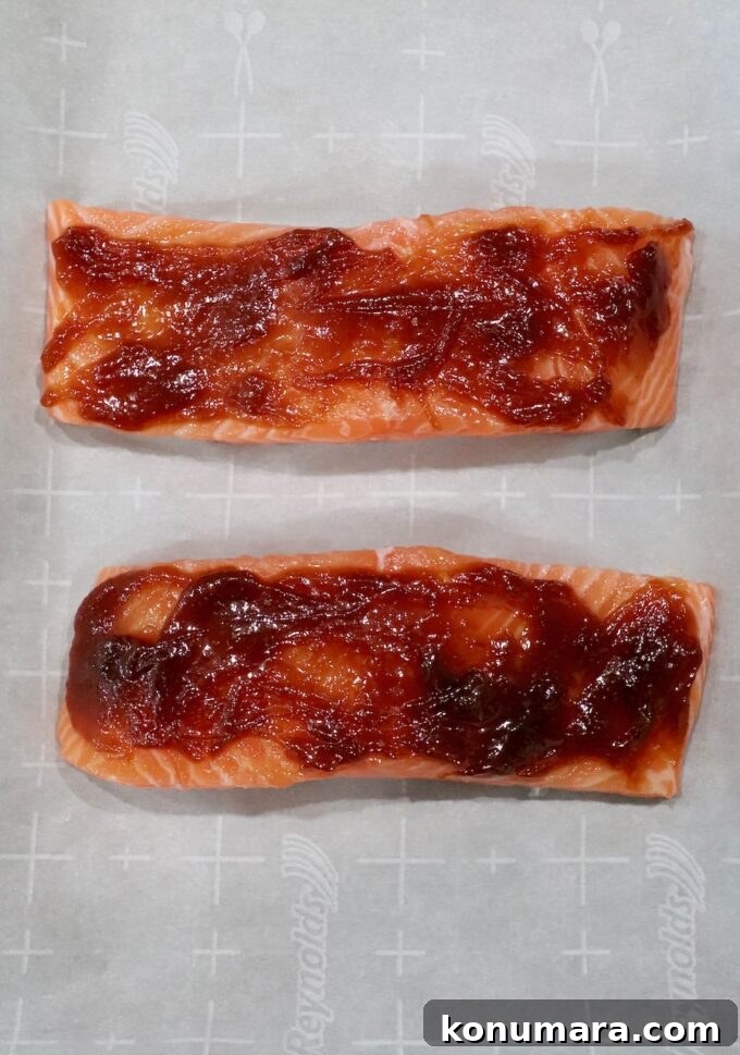 salmon filets on parchment lined baking sheet topped with miso glaze
