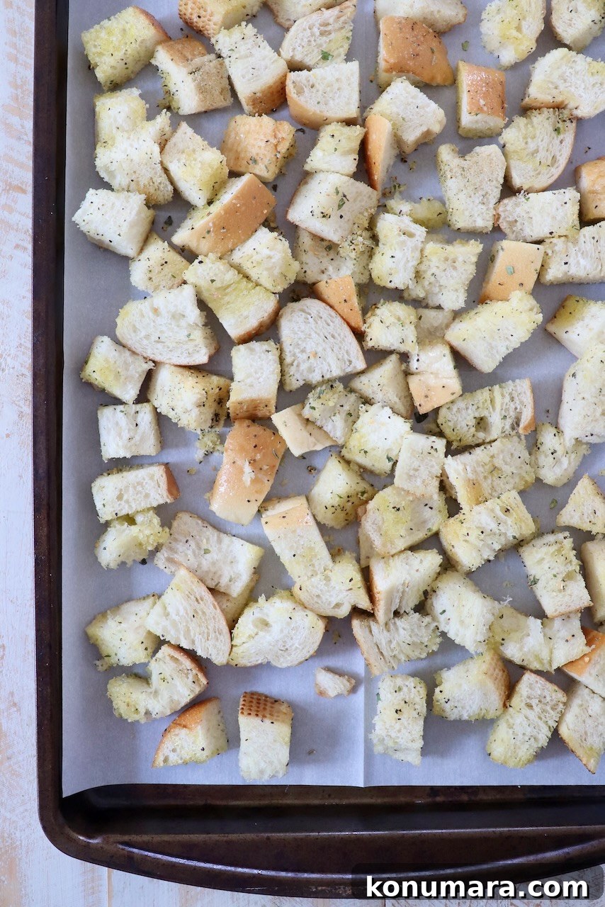 How to Make Crispy Homemade Croutons 4 seasoned cubes of bread on parchment lined baking sheet