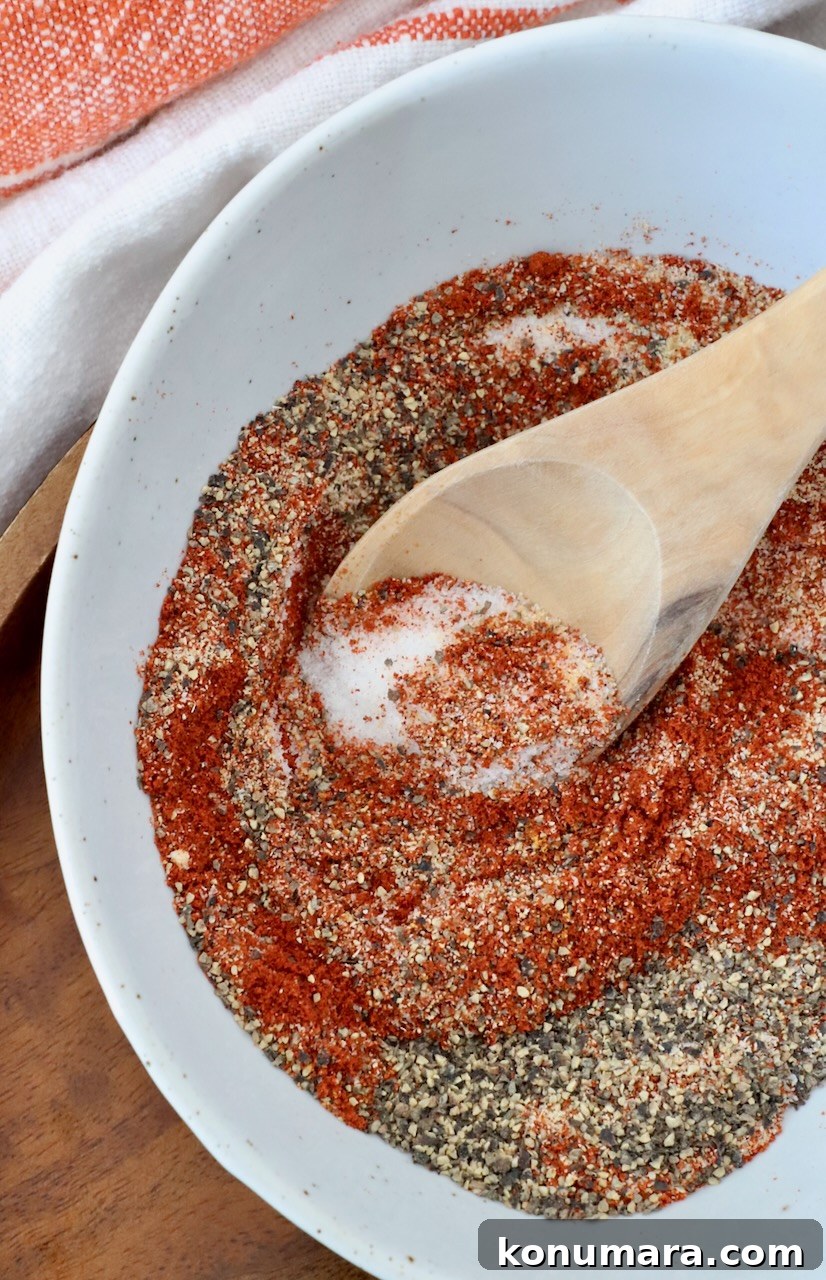 Homemade Hamburger Seasoning Mix for Juicy Burgers 6 spices mixed together in bowl with wooden spoon