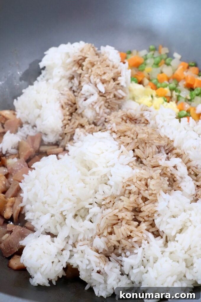 Classic Ham Fried Rice Recipe with Eggs and Peas 7 cooked rice in skillet covered with soy sauce