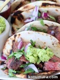 Grilled Flat Iron Steak Tacos with Cilantro Lime Slaw 15 steak tacos topped with guacamole on plate
