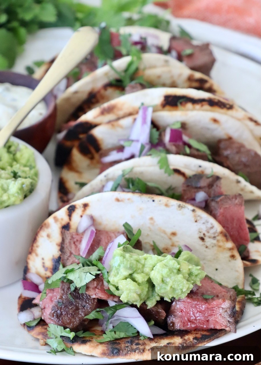Grilled Flat Iron Steak Tacos with Cilantro Lime Slaw 7 steak tacos on plate topped with guacamole