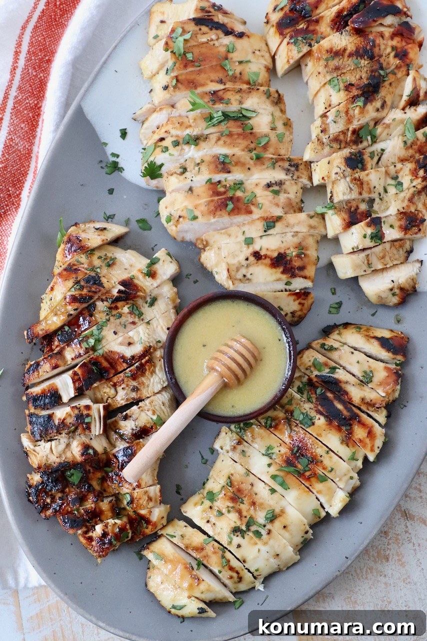 sliced grilled chicken on plate with small bowl of sauce in the middle