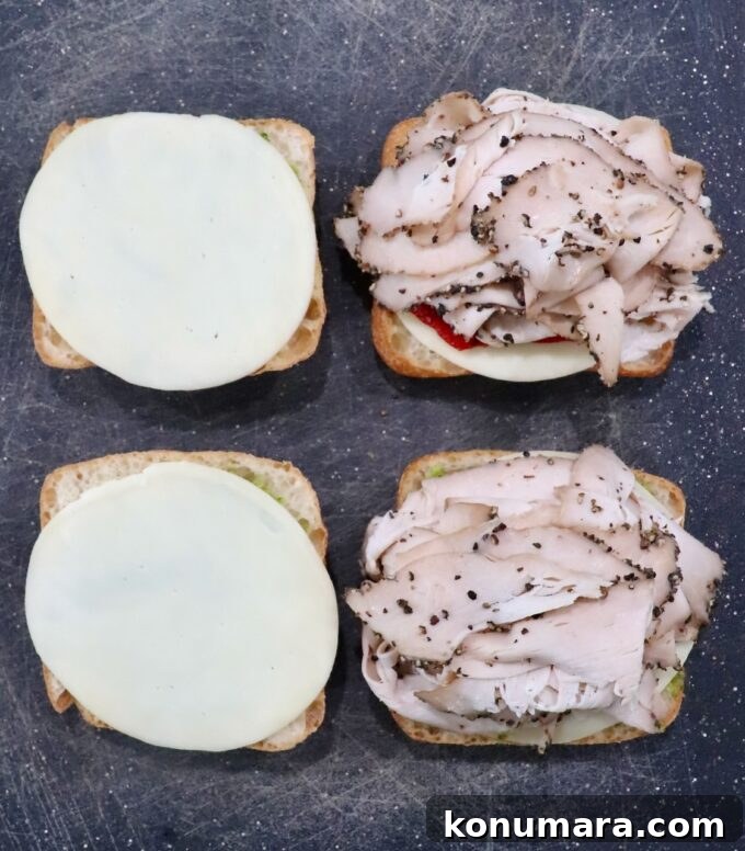 Grilled Turkey Pesto Sandwich with Melted Mozzarella 6 sliced turkey on top of cheese slices on rolls