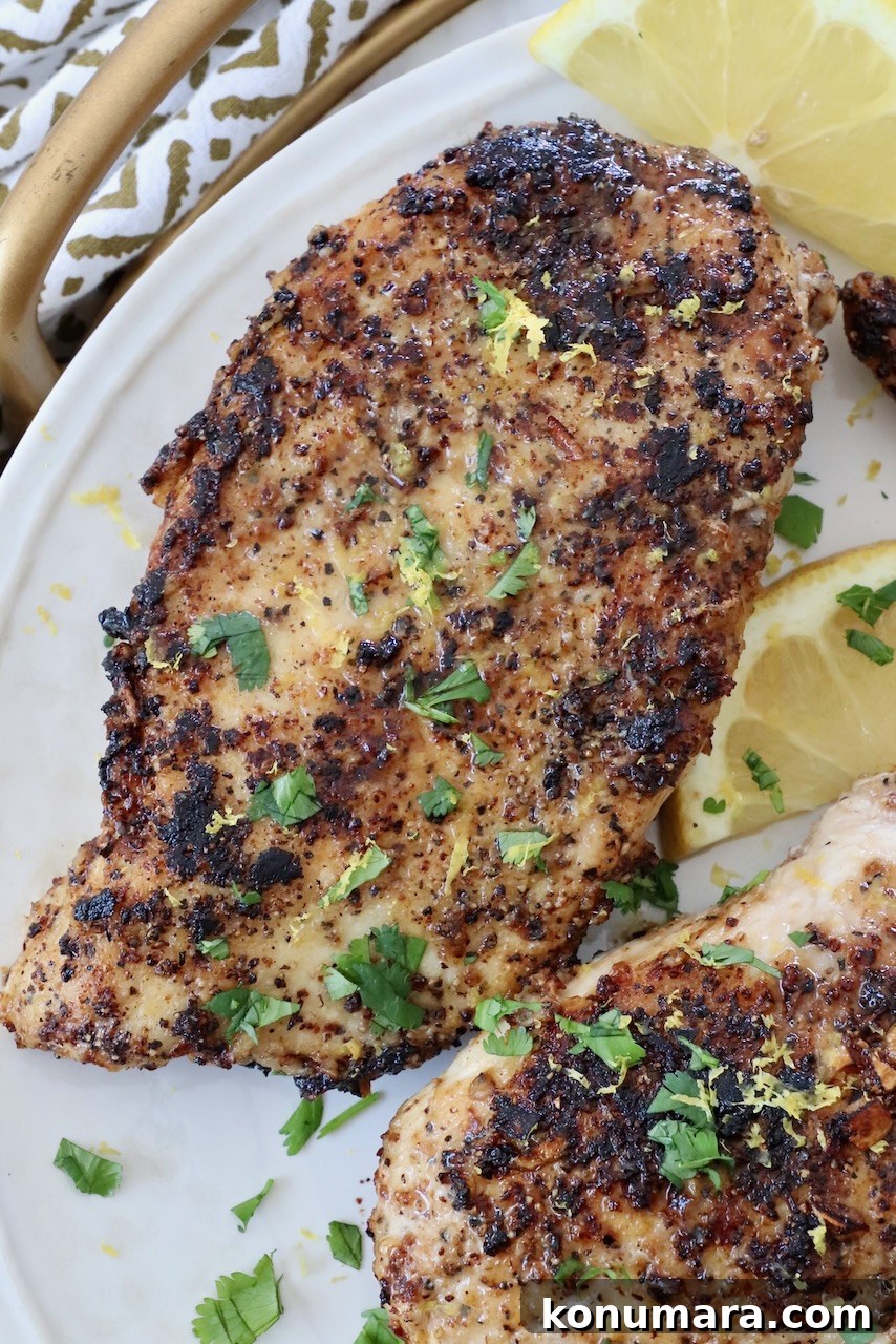 cooked lemon pepper chicken breasts on plate with lemon slices