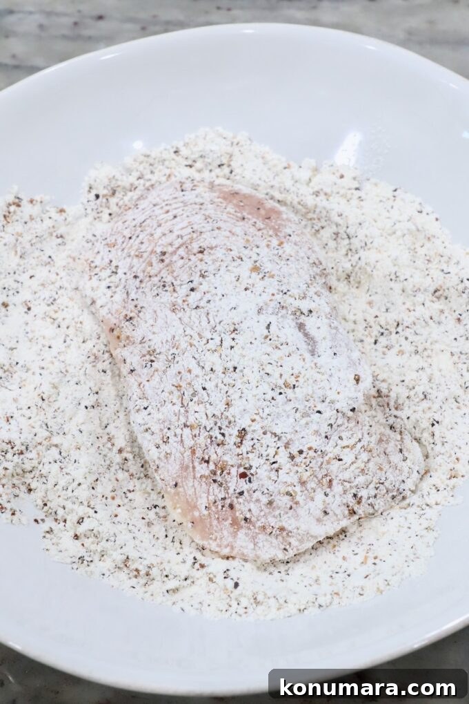 Crispy Lemon Pepper Chicken Recipe with Garlic Butter 5 chicken breast in bowl of seasoned flour