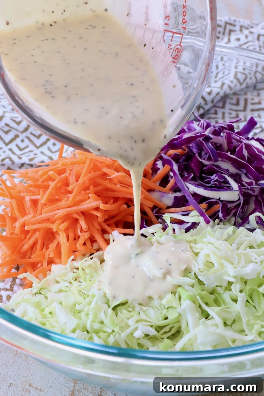 Homemade Creamy Coleslaw Dressing Recipe 6 coleslaw dressing poured from glass measuring cup over cabbage in a large glass bowl