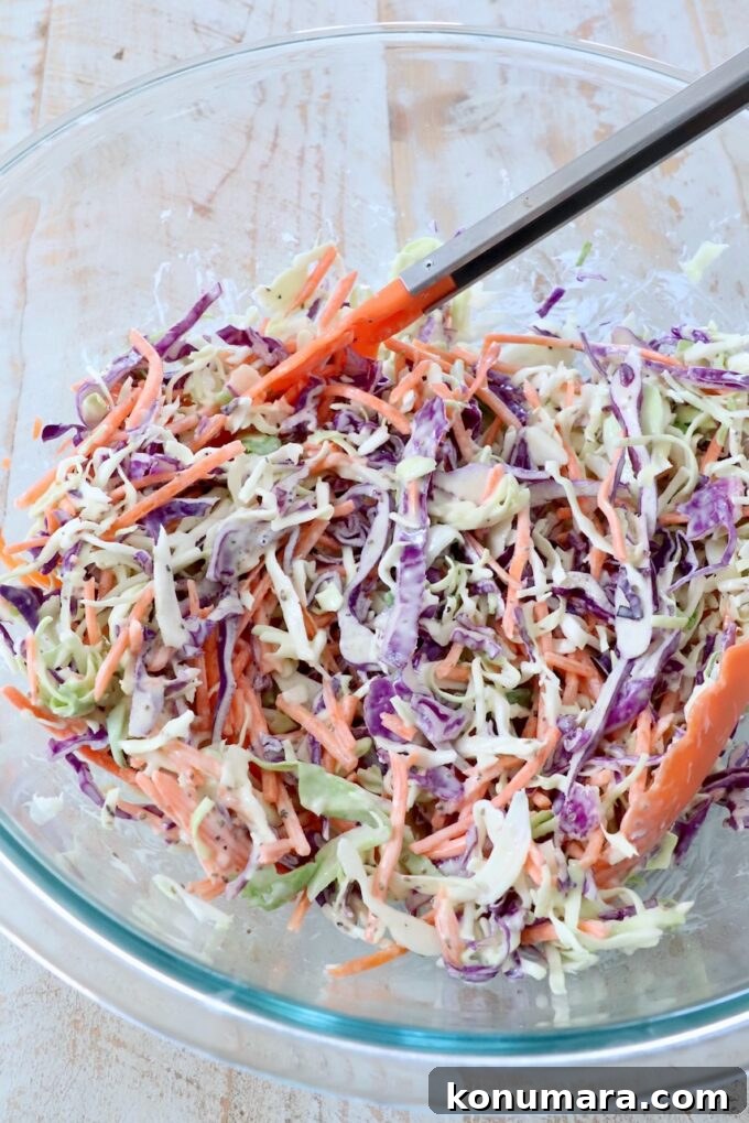 Classic Creamy Coleslaw Recipe 5 prepared coleslaw in large glass bowl with kitchen tongs