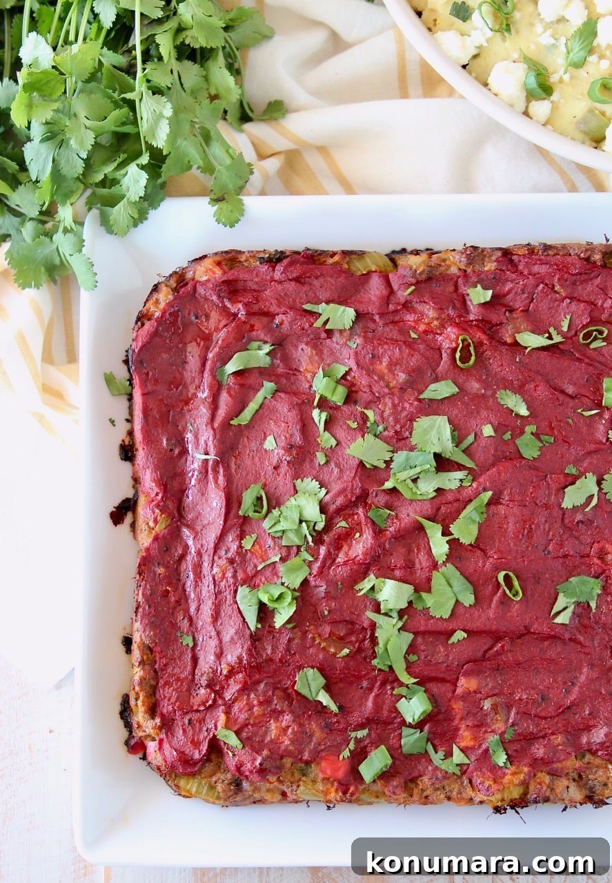Cooked Mexican meatloaf on white plate topped with tomato paste and cilantro