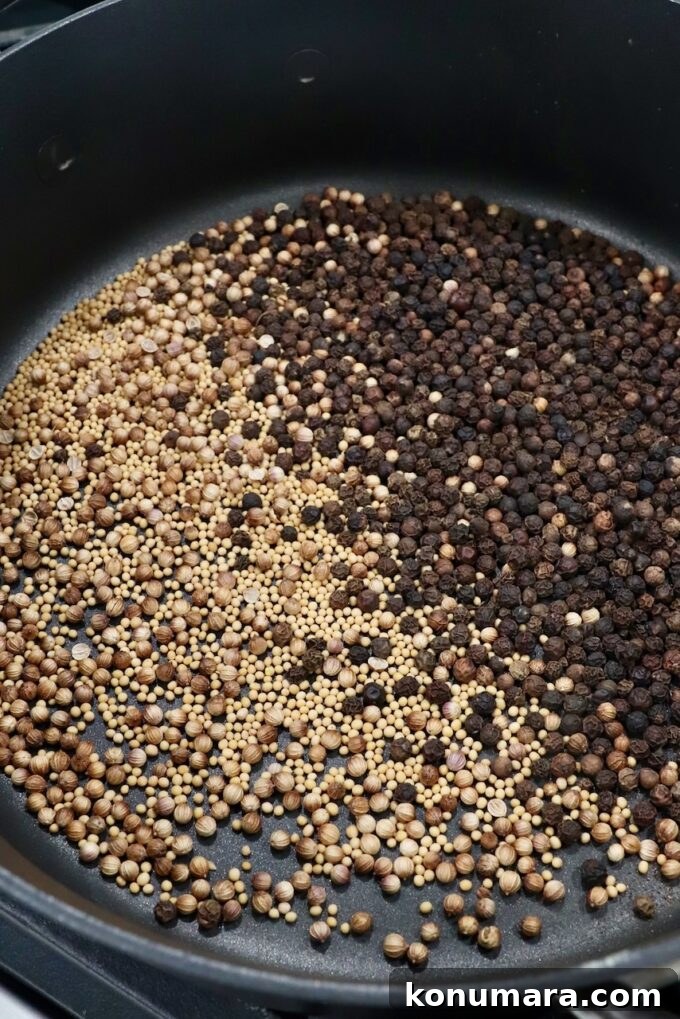 peppercorns, coriander seeds and mustard seeds toasting in skillet