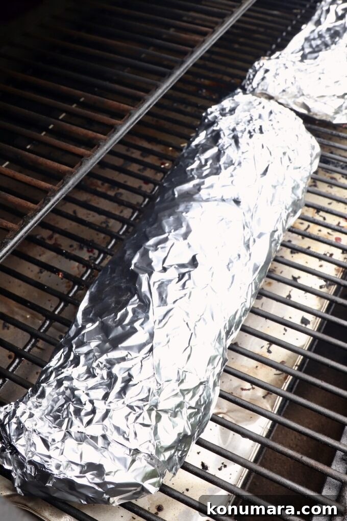 rack of ribs wrapped in foil on a smoker