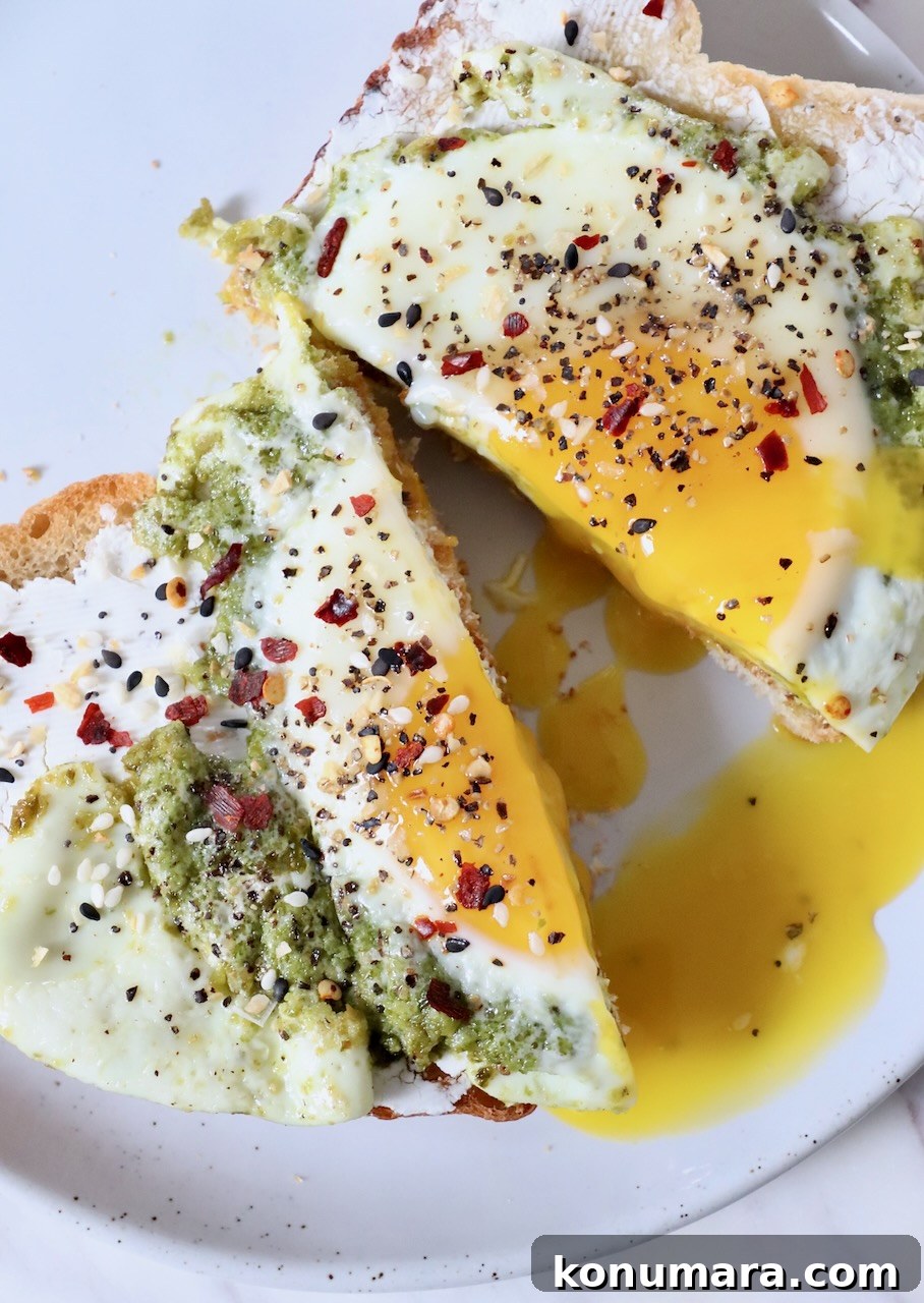 Creamy Pesto Scrambled Eggs with Parmesan 2 pesto eggs on toast cut in half on plate