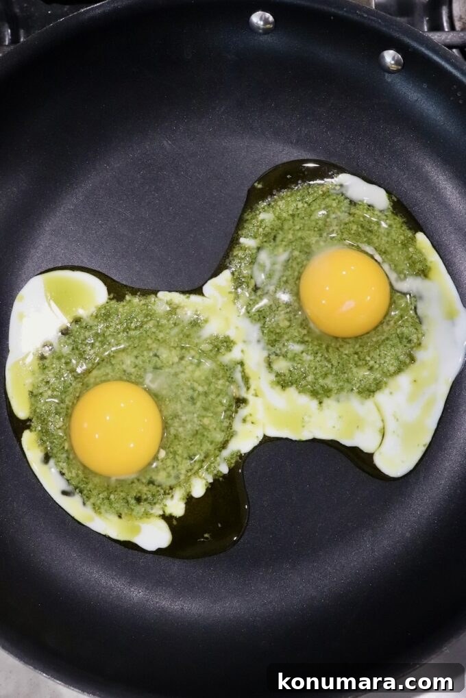 Creamy Pesto Scrambled Eggs with Parmesan 7 eggs cracked on top of pesto in skillet