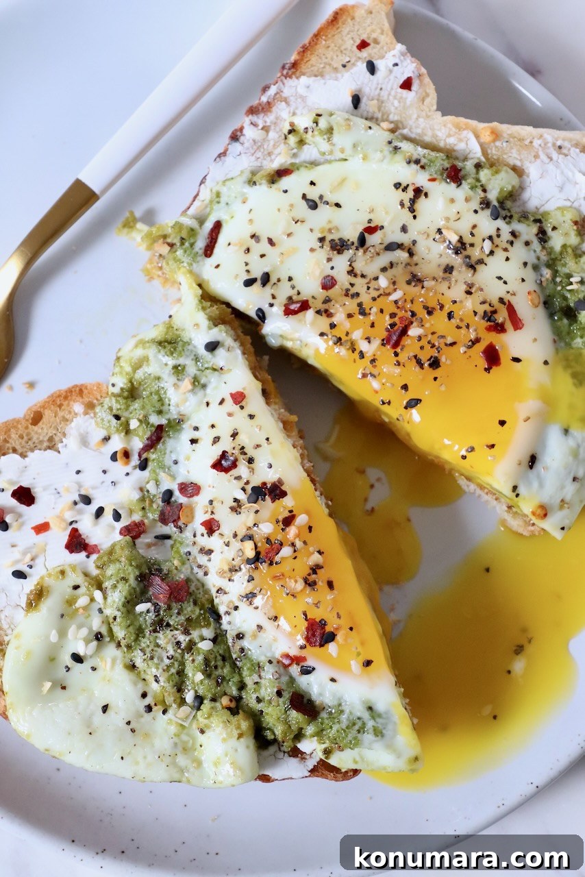 Creamy Pesto Scrambled Eggs with Parmesan 10 pesto egg on top of toast, sliced in half, on plate