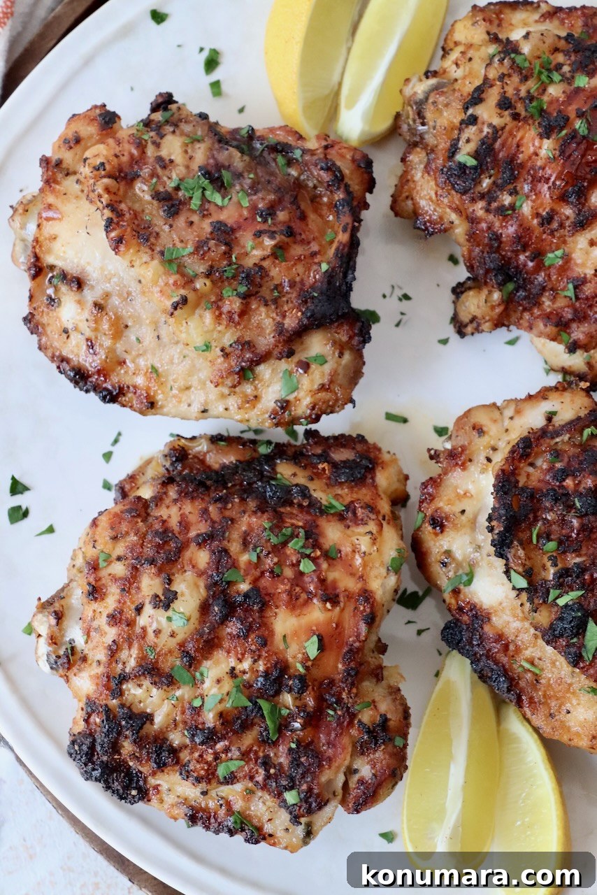 Crispy Garlic Air Fryer Chicken Thighs Recipe 2 cooked chicken thighs on plate with lemon wedges