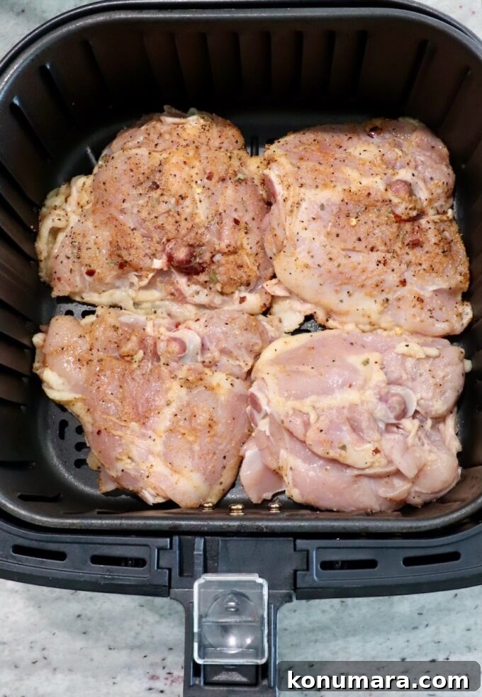 Crispy Garlic Air Fryer Chicken Thighs Recipe 4 seasoned raw bone-in chicken thighs in air fryer basket