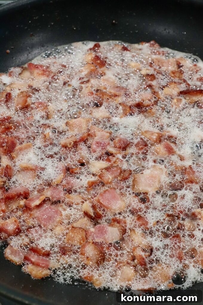 Diced bacon frying in a skillet