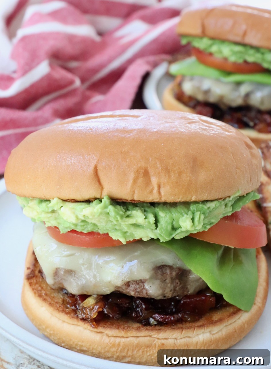 burger on plate topped with smashed avocado, lettuce and tomato