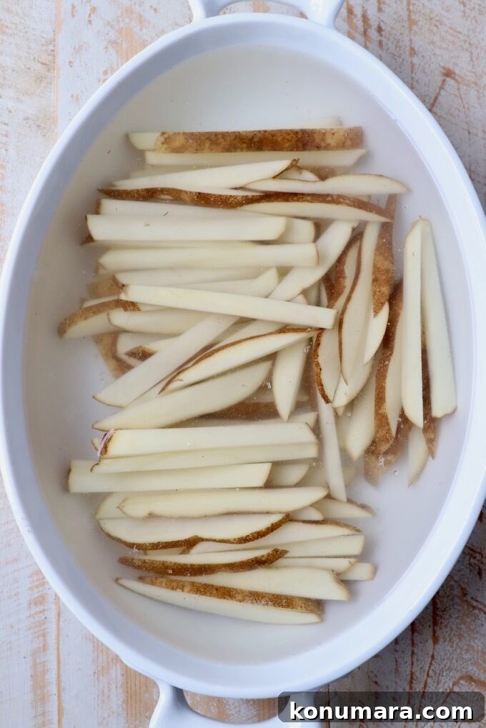 Crispy Truffle Fries with Garlic and Parmesan 4 sliced potatoes soaking in casserole dish filled with water