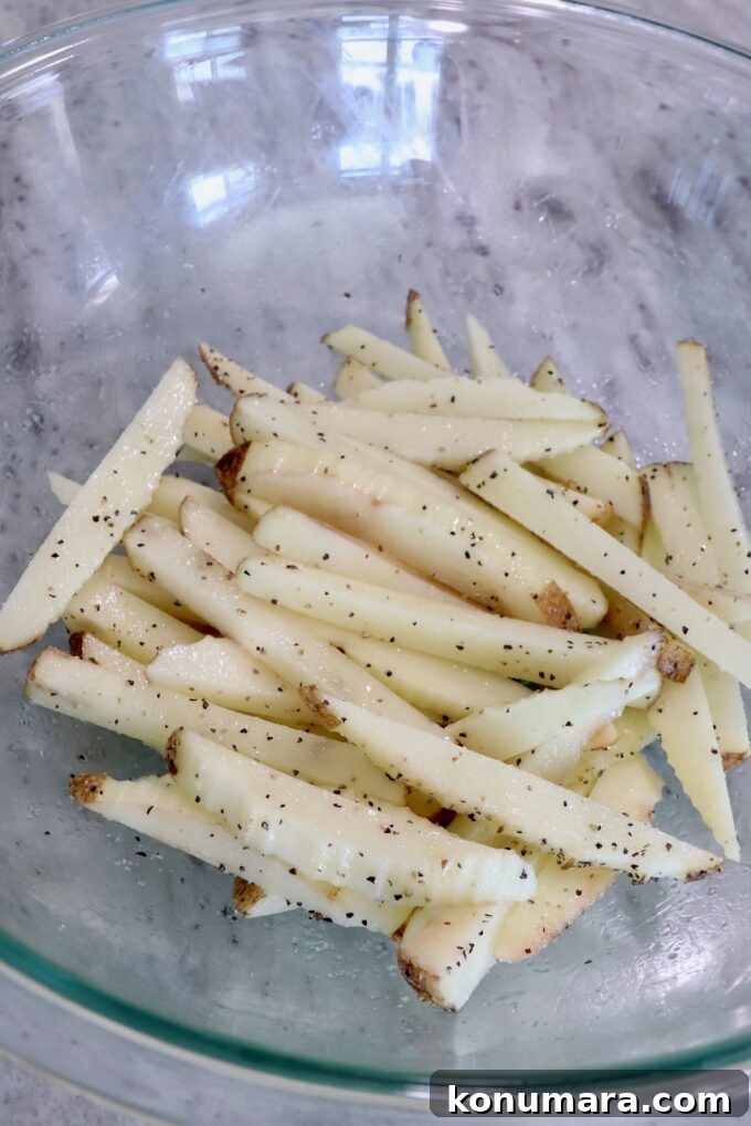 Crispy Truffle Fries with Garlic and Parmesan 5 seasoned potatoes cut into french fries in glass bowl