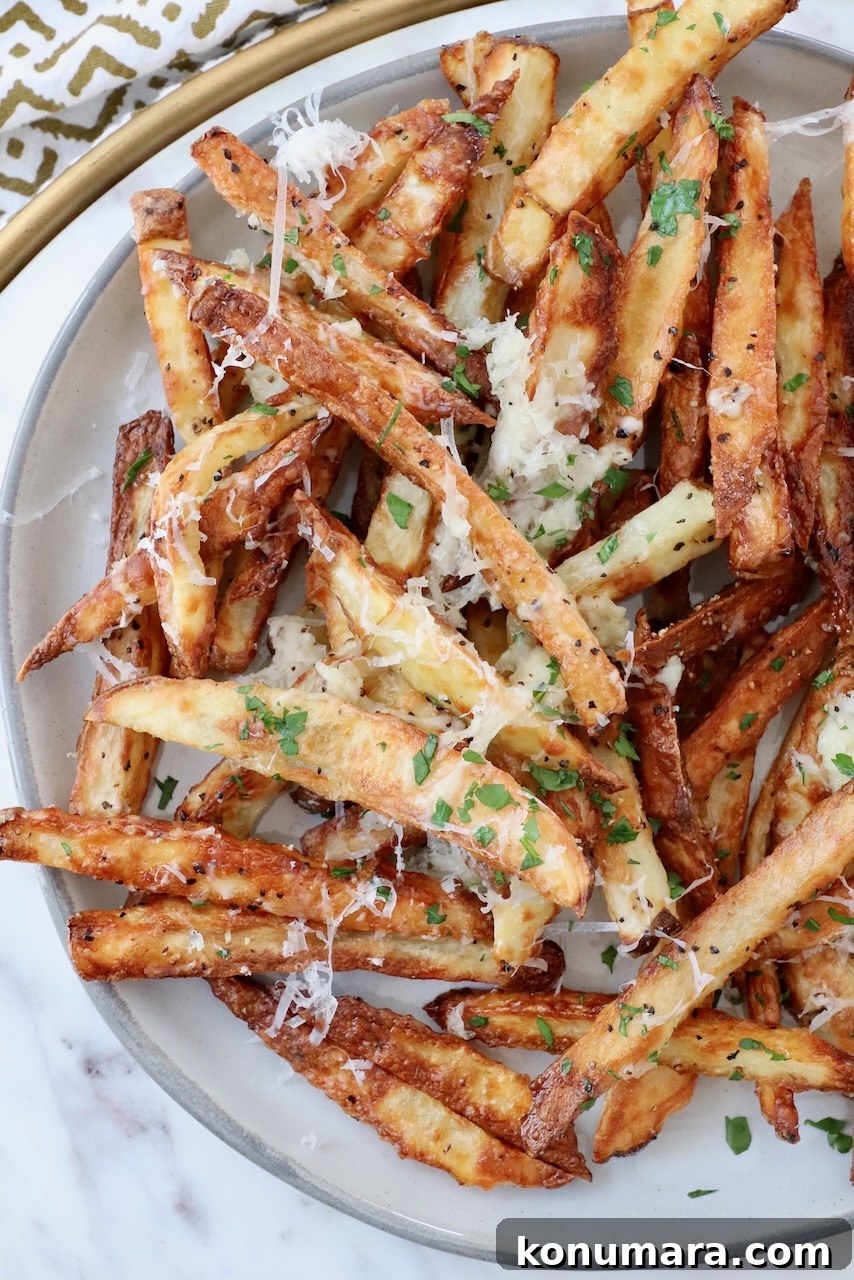 Crispy Truffle Fries with Garlic and Parmesan 8 cooked french fries on plate topped with grated parmesan cheese