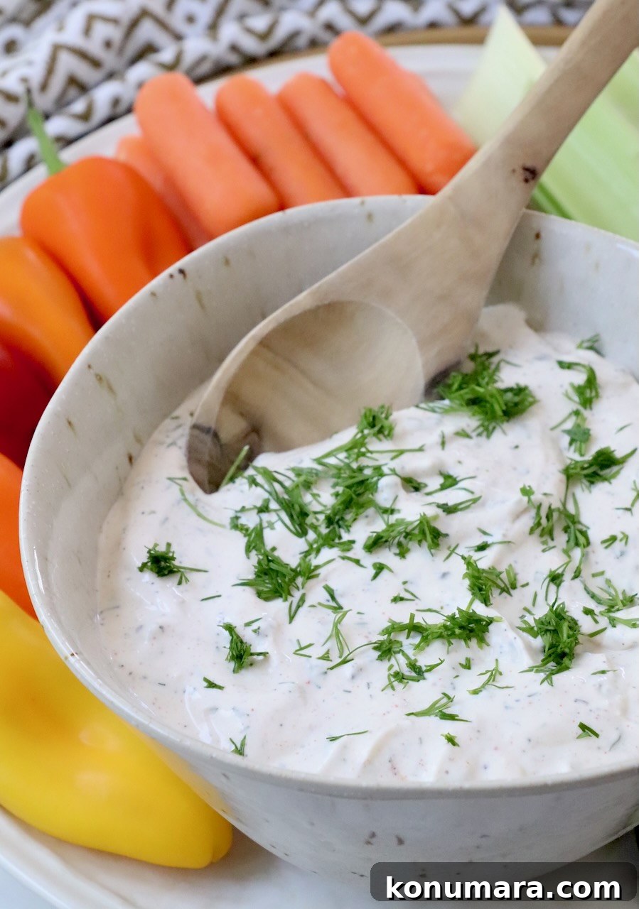 creamy dip topped with chopped dill in bowl with spoon