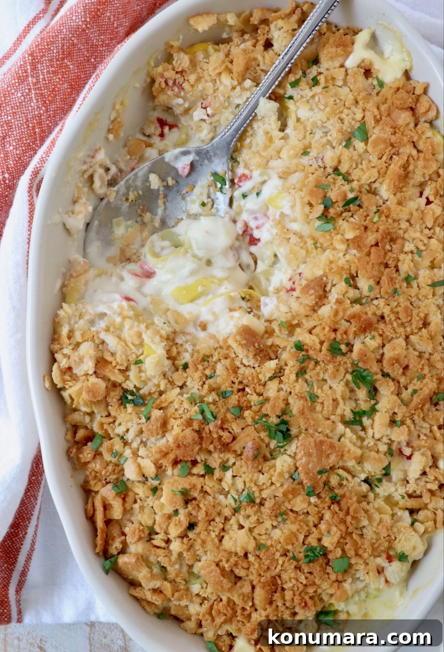 squash casserole topped with ritz cracker topping in baking dish with serving spoon