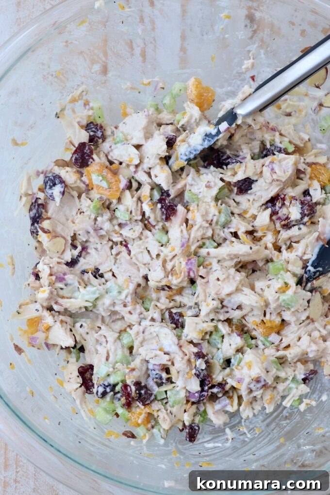 Classic Creamy Chicken Salad with Celery and Fresh Herbs 5 chicken salad prepared in a large glass bowl with kitchen tongs