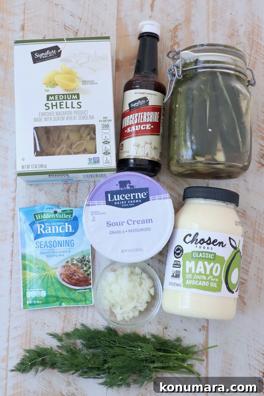 Creamy Tangy Pickle Pasta Salad 3 ingredients for dill pickle pasta salad on white wood board