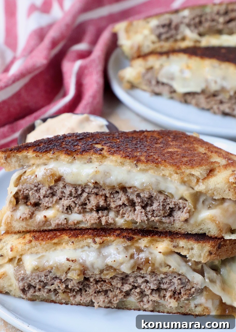 Classic Patty Melt Recipe with Caramelized Onions 2 patty melt sandwich cut in half stacked up on each other on plate