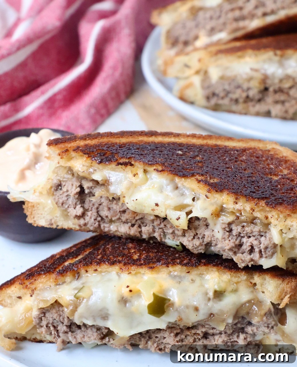 Classic Patty Melt Recipe with Caramelized Onions 4 patty melt sliced in half and stacked up on a plate