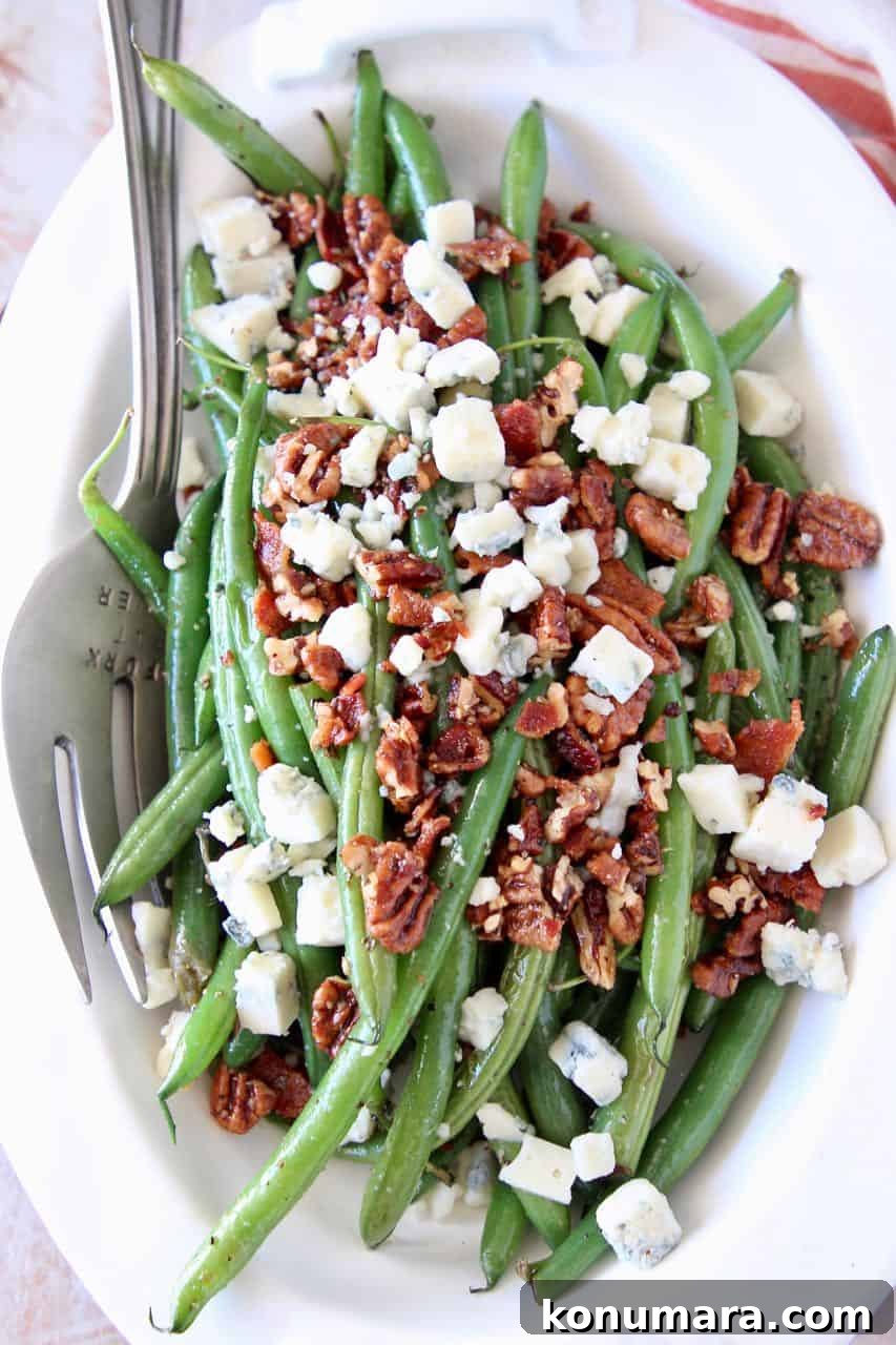 Fresh green beans in bowl topped with bacon crumbles, chopped pecans and blue cheese