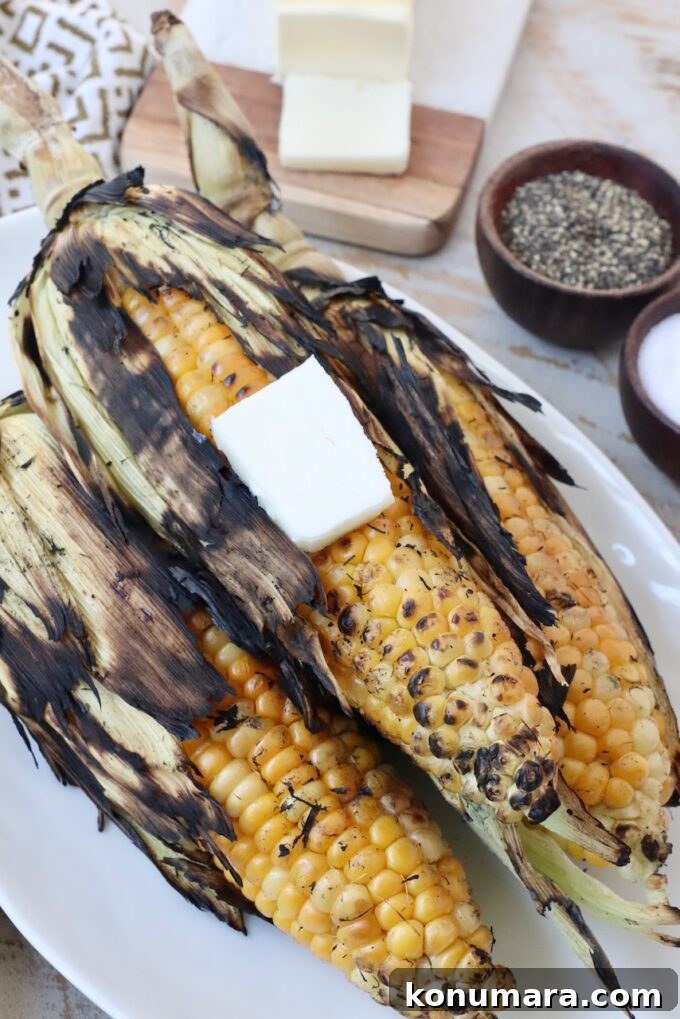 Grilled corn with husks on plate with butter on top