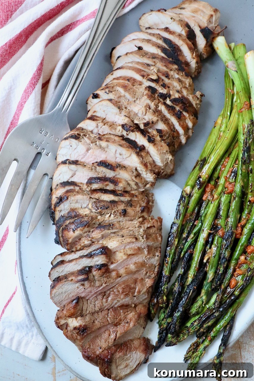 Savory Pork Tenderloin Marinade for Tender, Juicy Meat 8 sliced grilled pork tenderloin on plate with grilled asparagus