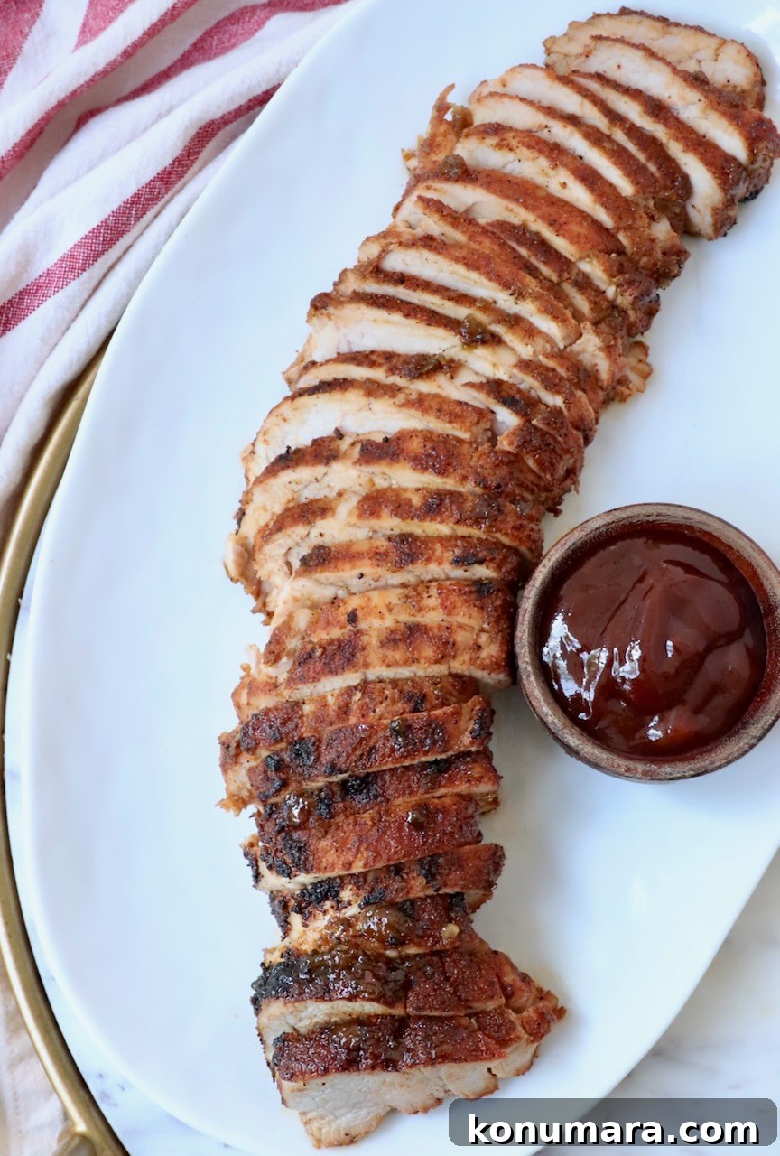 Grilled Pork Tenderloin Recipe with Garlic-Herb Rub 2 sliced grilled pork tenderloin on plate with a small bowl of bbq sauce on the side