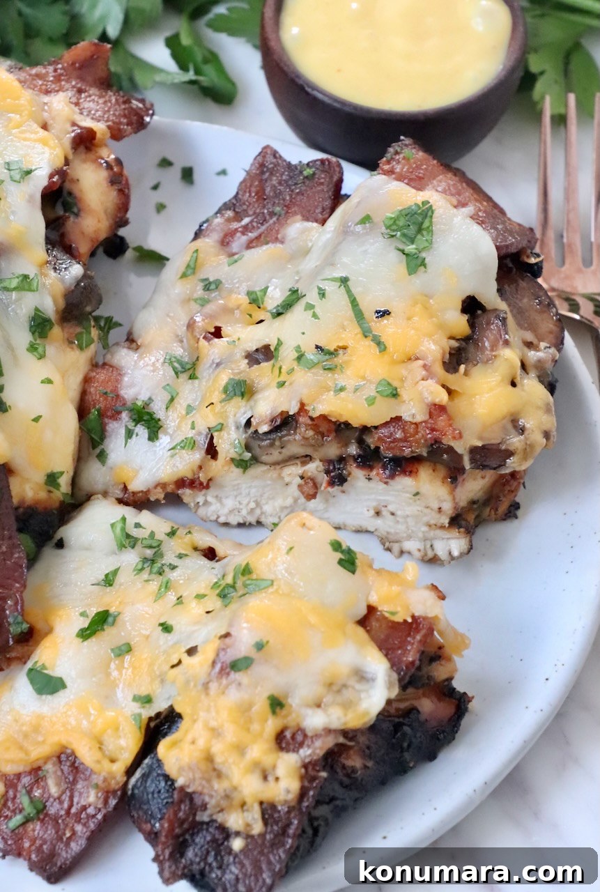 grilled chicken topped with bacon and cheese sliced in half on plate