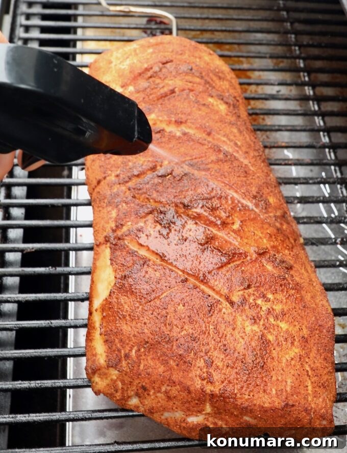 How to Smoke Pork Loin for Tender, Juicy Results 6 seasoned pork loin on smoker sprayed with apple juice