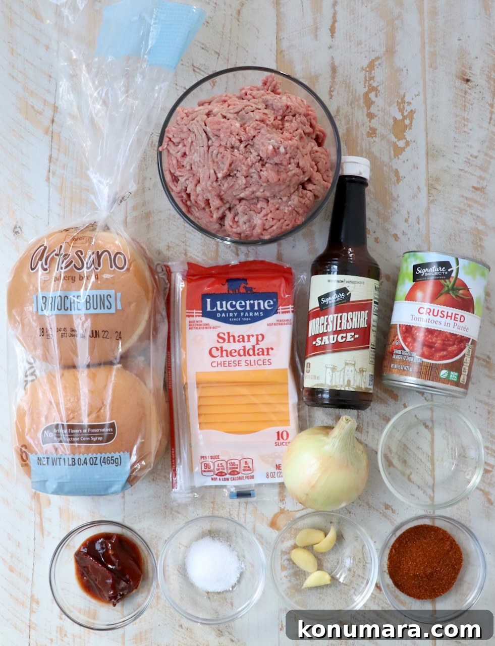 ingredients for chili cheeseburgers on white wood board