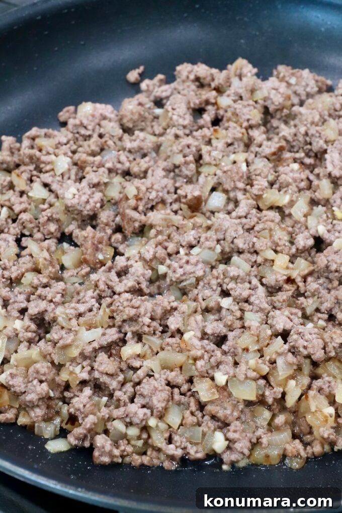 cooked ground beef with diced onions in a skillet