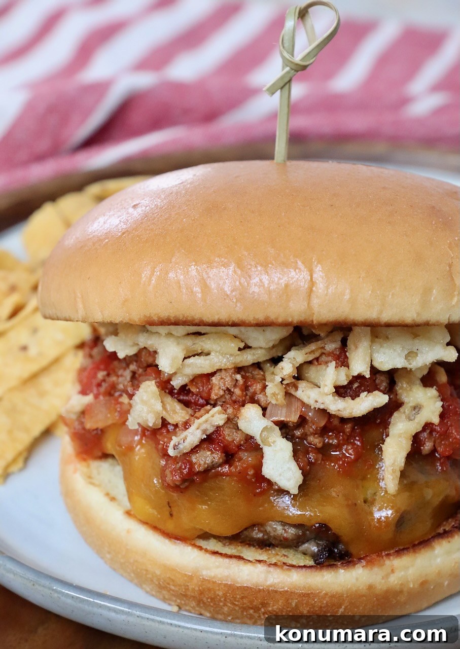 chili cheeseburger on plate topped with fried onion strings