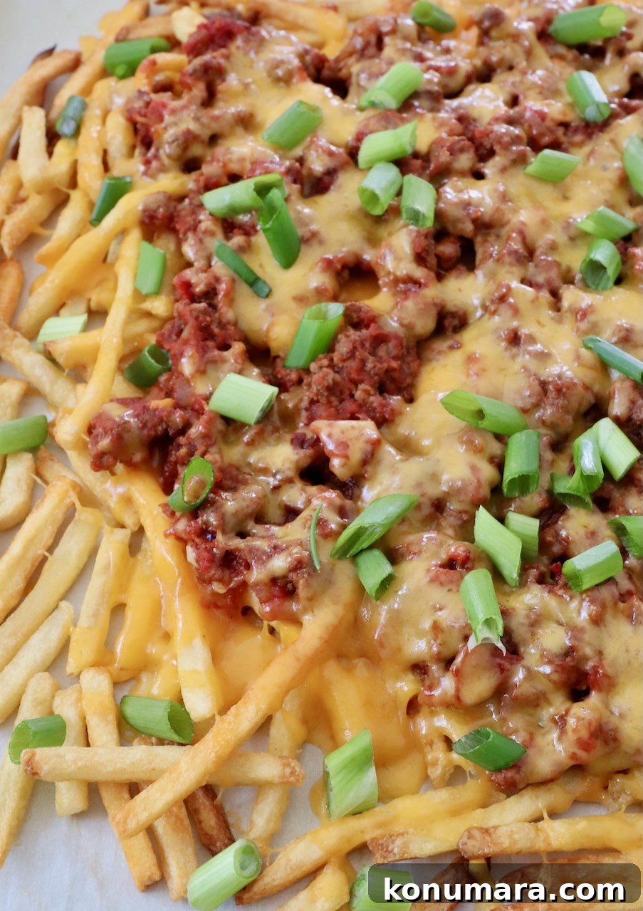 chili cheese fries on parchment lined baking sheet
