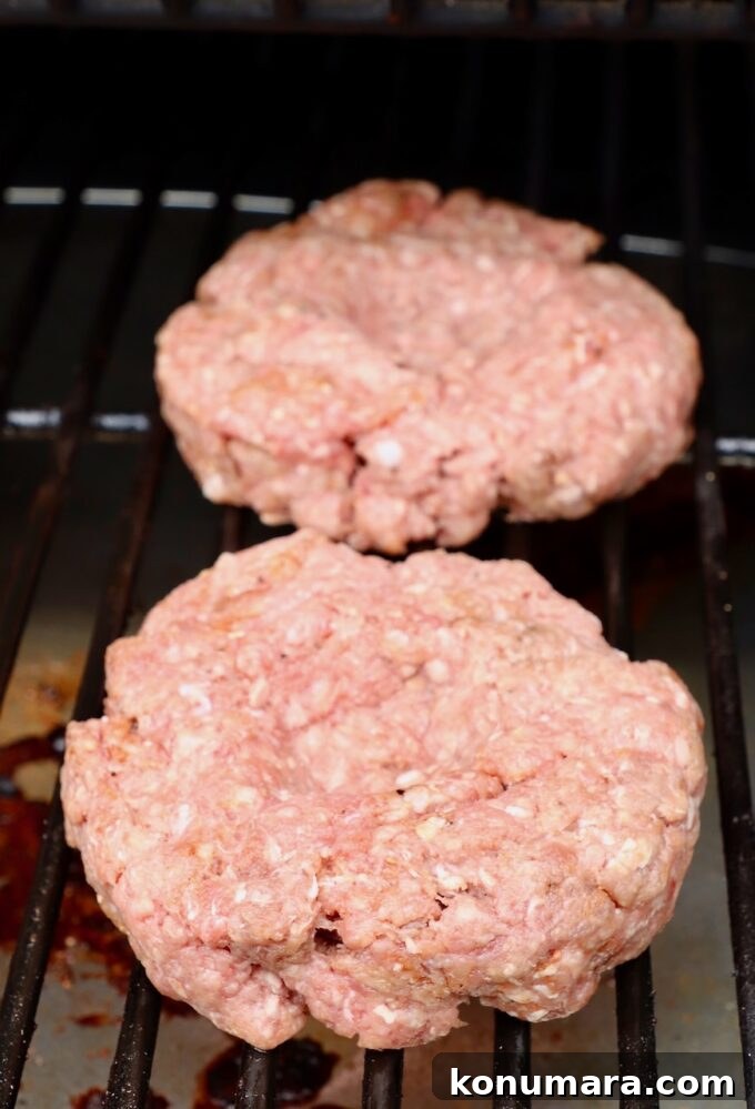 raw burger patties on a smoker