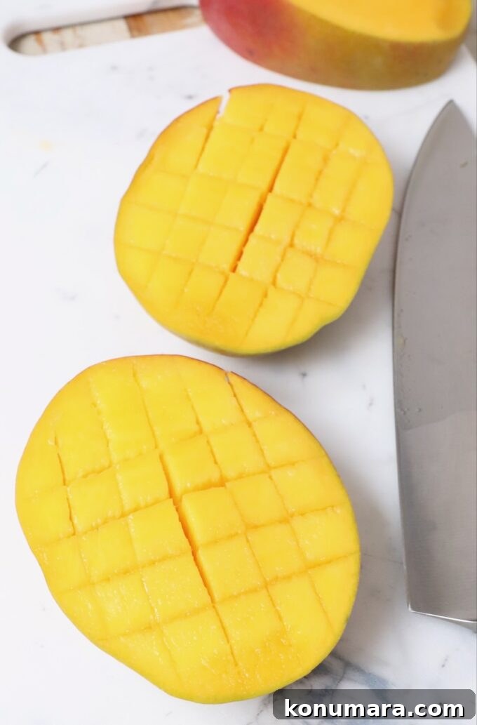 mango sliced into cubes on cutting board with knife