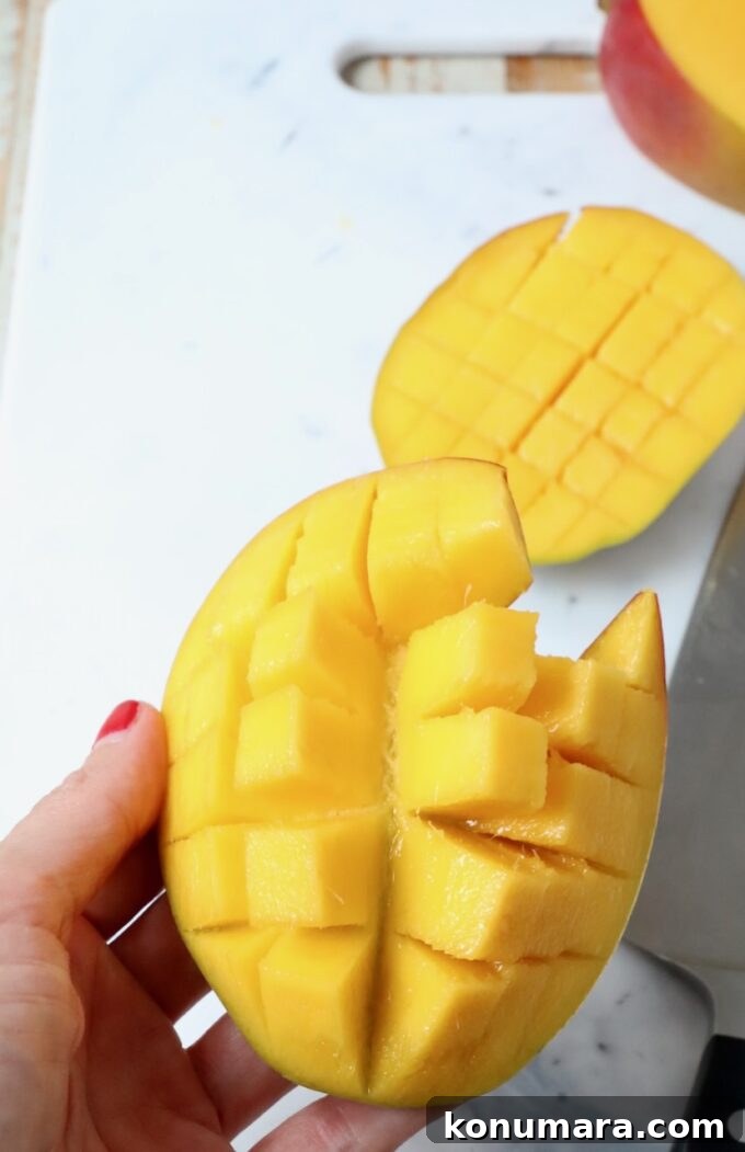 hand holding sliced mango over cutting board