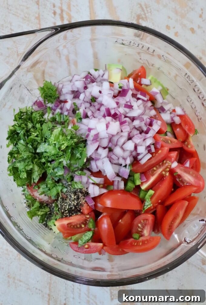 diced veggies in glass bowl with cilantro, salt and pepper