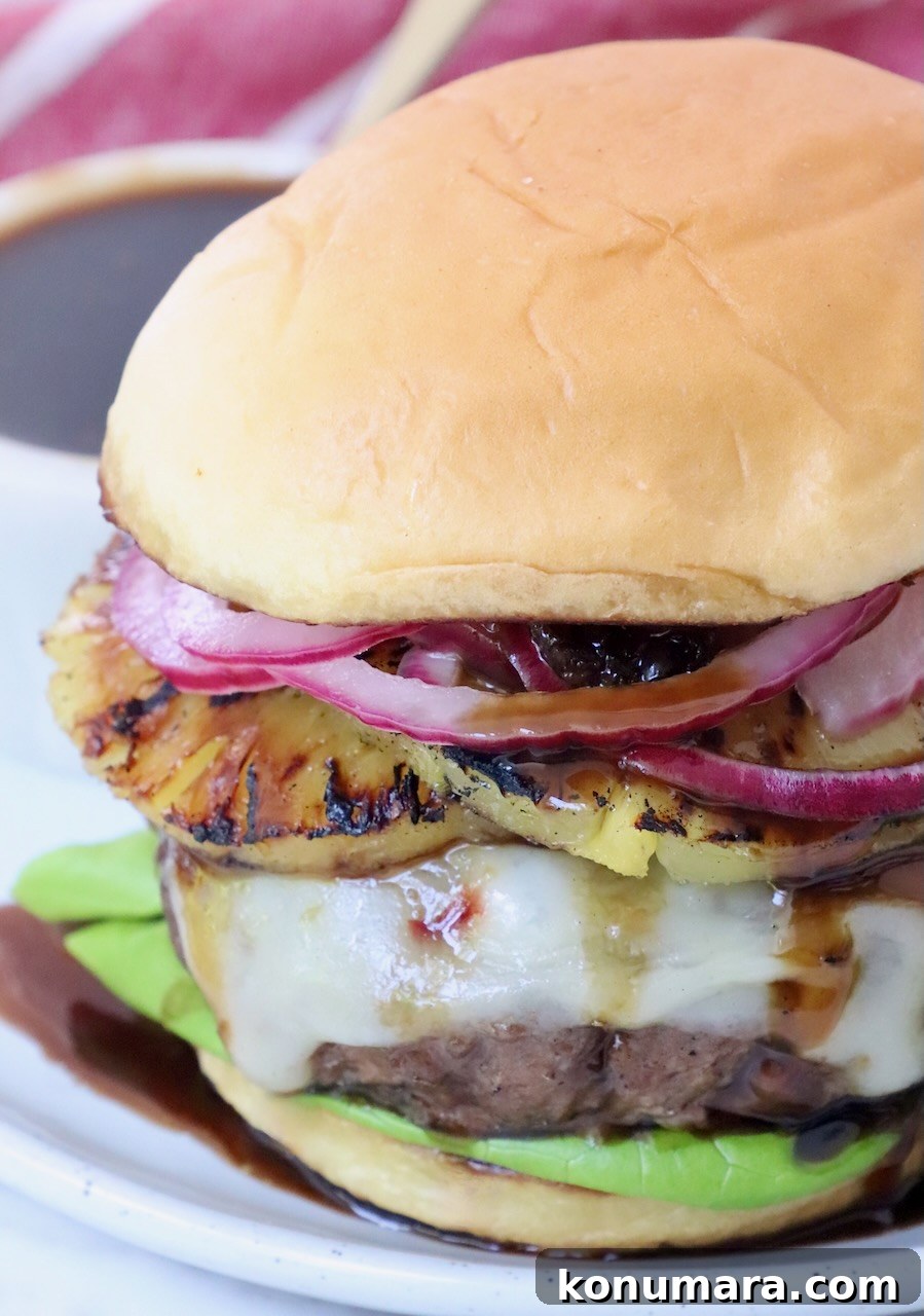 Hawaiian Burger with Grilled Pineapple and Teriyaki Sauce 2 cheeseburger on plate topped with grilled pineapple and pickled onions