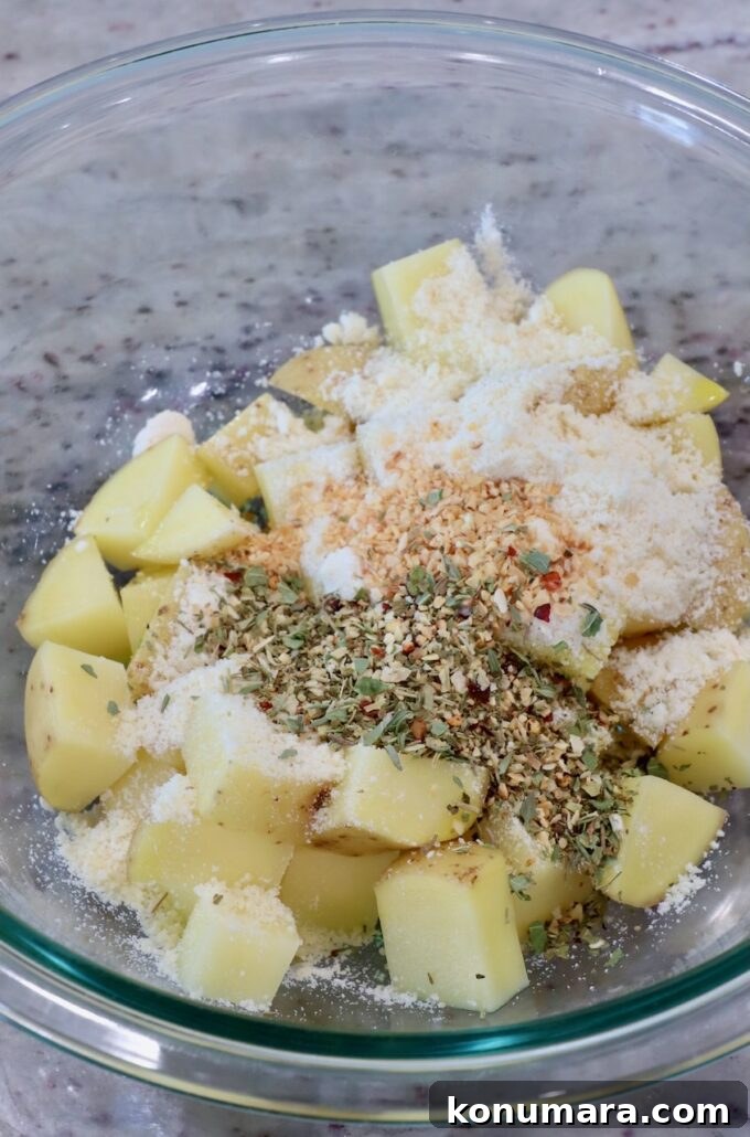 cubed potatoes with spices and parmesan cheese in glass bowl