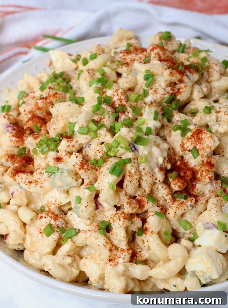 creamy pasta salad in bowl topped with paprika and diced chives