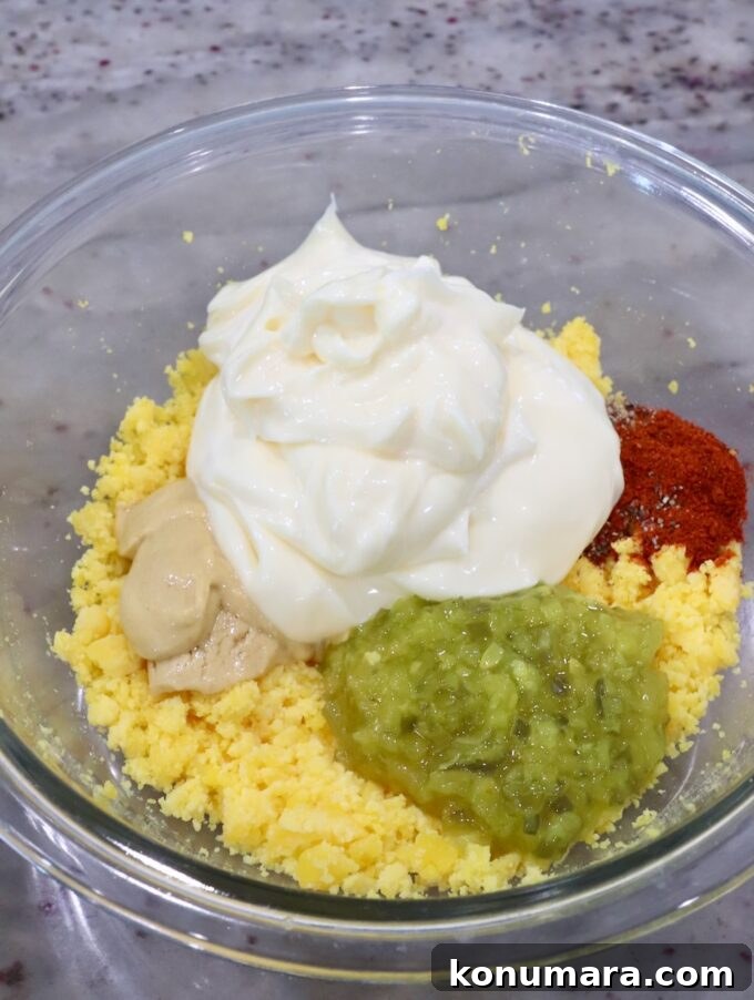 mashed egg yolks in a glass bowl with mayonnaise, relish, dijon mustard and spices