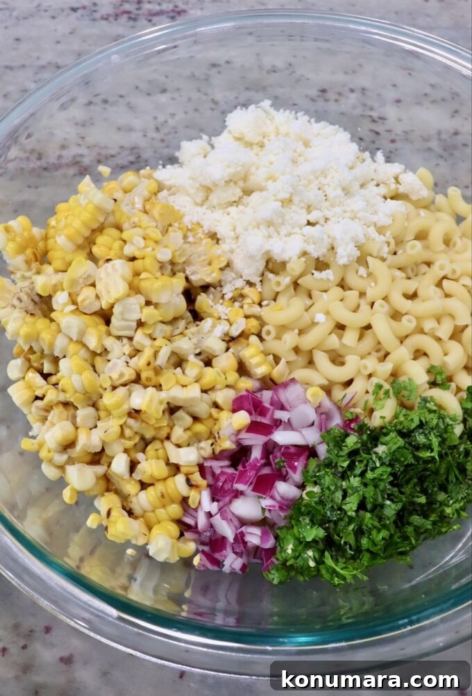 Elote Pasta Salad with Roasted Corn and Cotija 5 cooked pasta in large glass bowl with diced onions, cilantro, corn kernels and cotija cheese